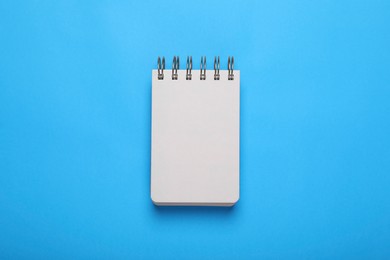 Photo of Open notebook on light blue background, top view