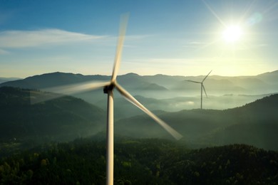 Image of Modern wind turbines in mountains on sunny day. Alternative energy source