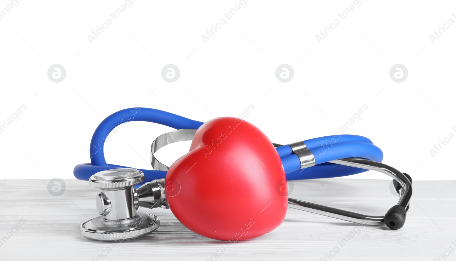 Photo of Stethoscope and red heart on wooden table against white background