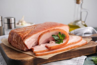 Photo of Delicious smoked bacon with parsley on table, closeup