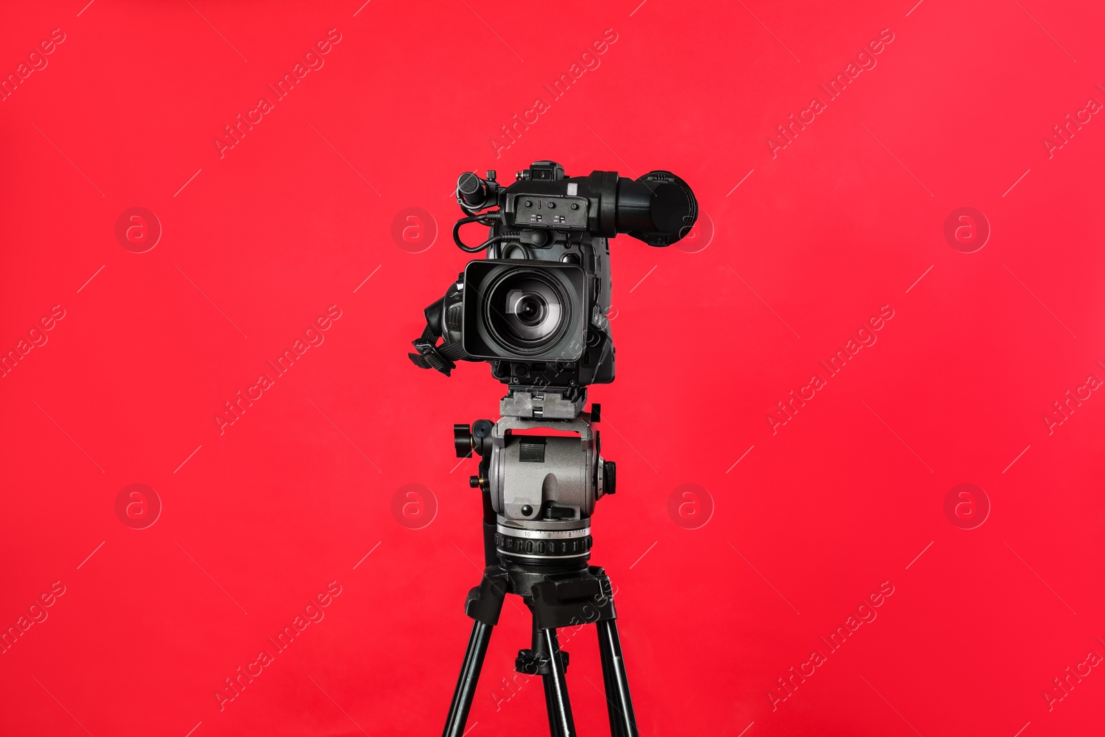 Photo of Modern professional video camera on red background