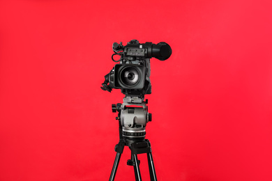 Photo of Modern professional video camera on red background