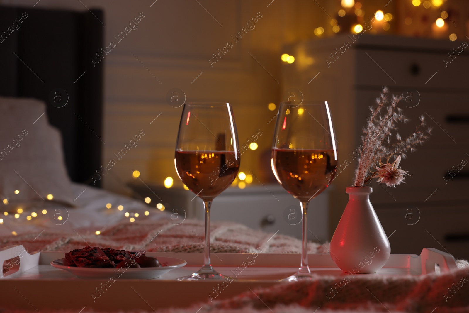 Photo of Glasses of wine in bedroom adorned for romantic evening