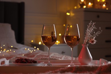 Glasses of wine in bedroom adorned for romantic evening