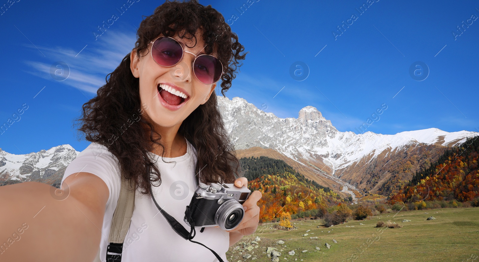 Image of Beautiful woman in sunglasses with camera taking selfie in mountains