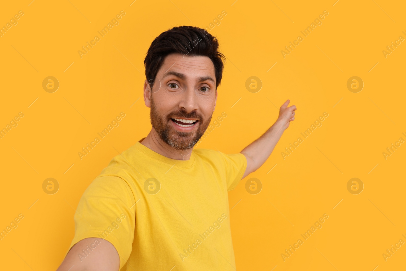 Photo of Smiling man taking selfie on yellow background, space for text