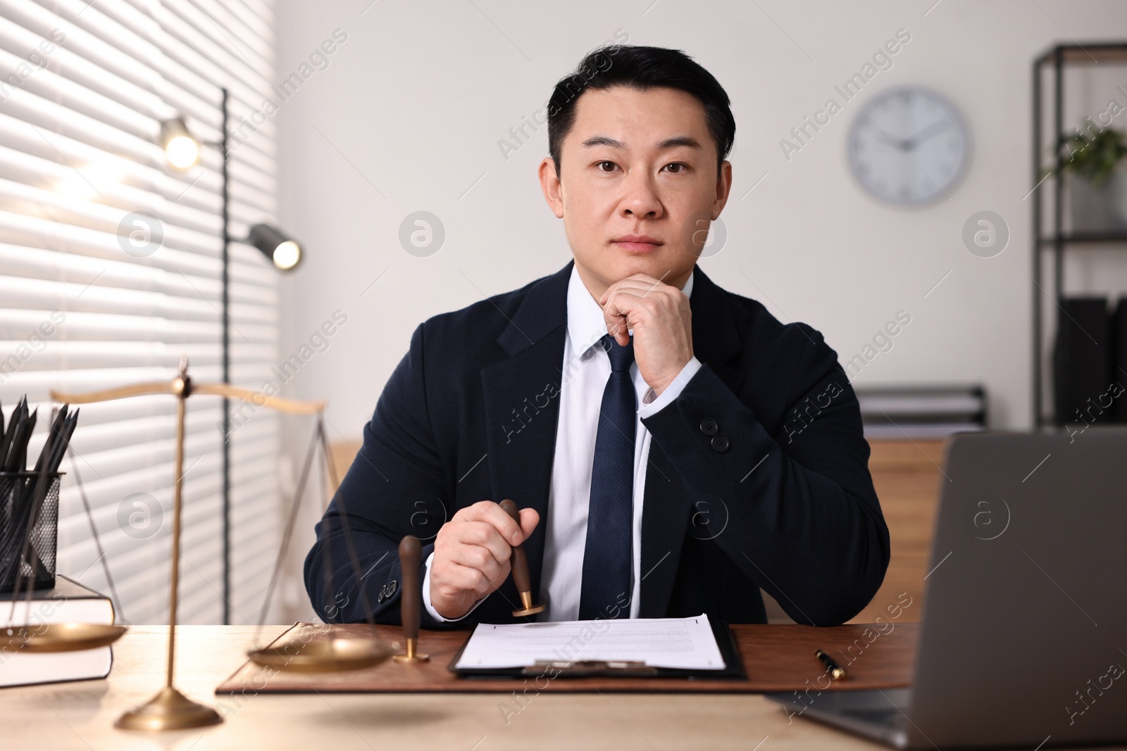 Photo of Notary stamping document at wooden table in office