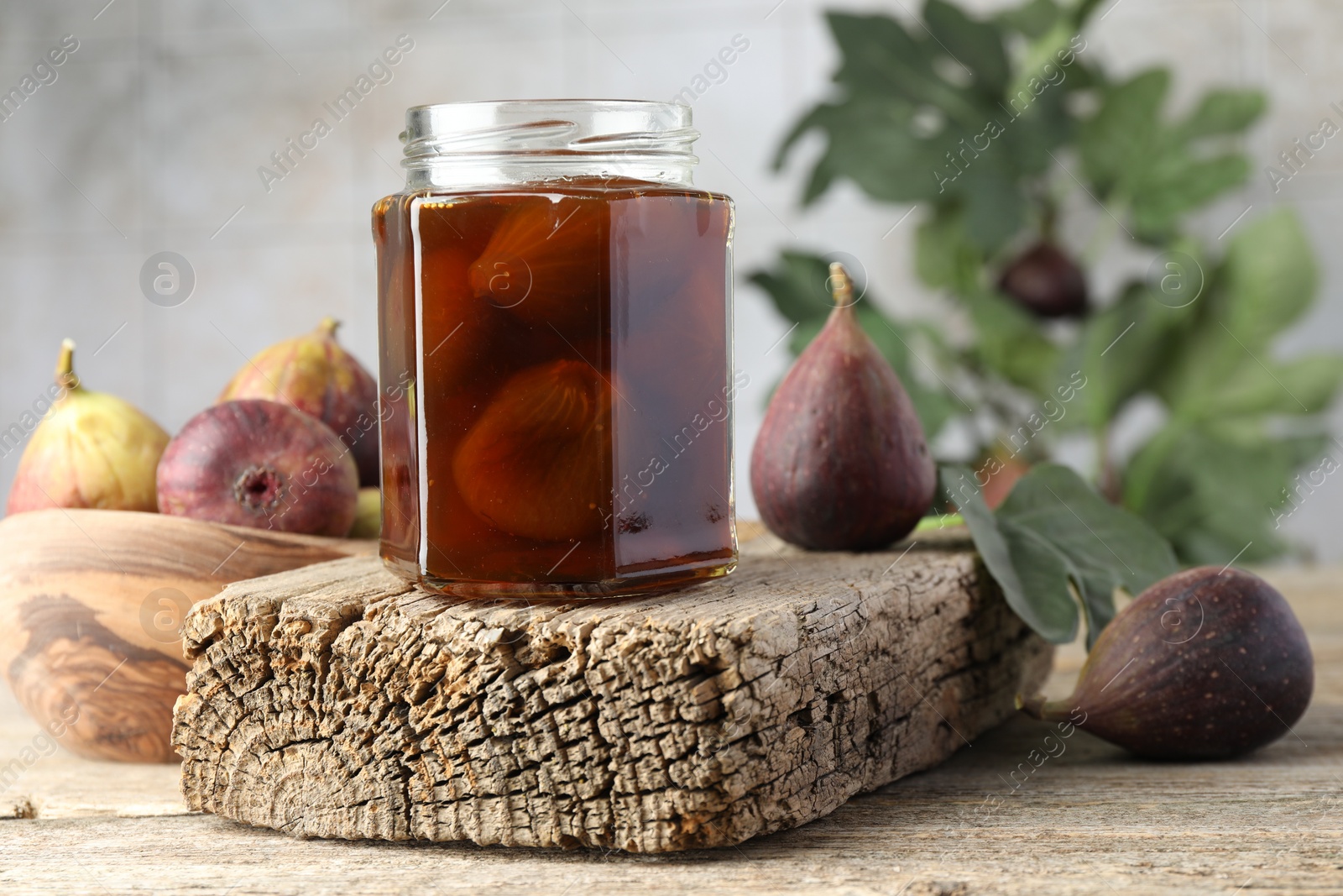 Photo of Jar of tasty sweet jam and fresh figs on wooden table