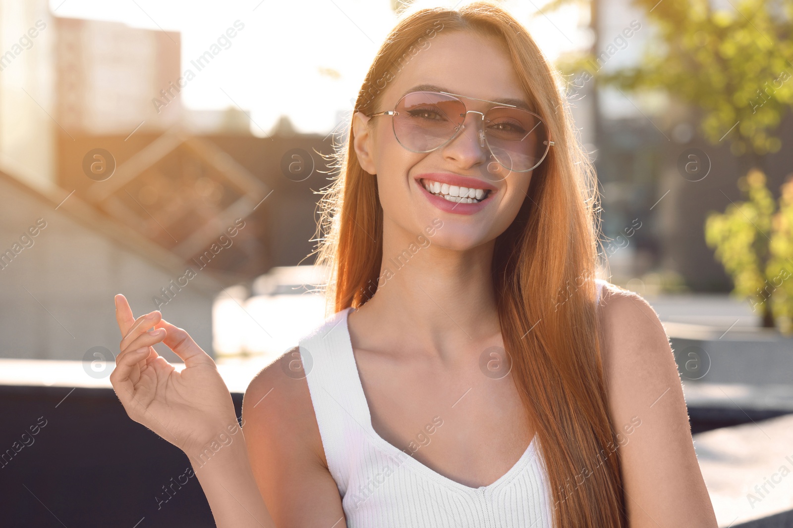 Photo of Beautiful smiling woman in sunglasses on city street, space for text