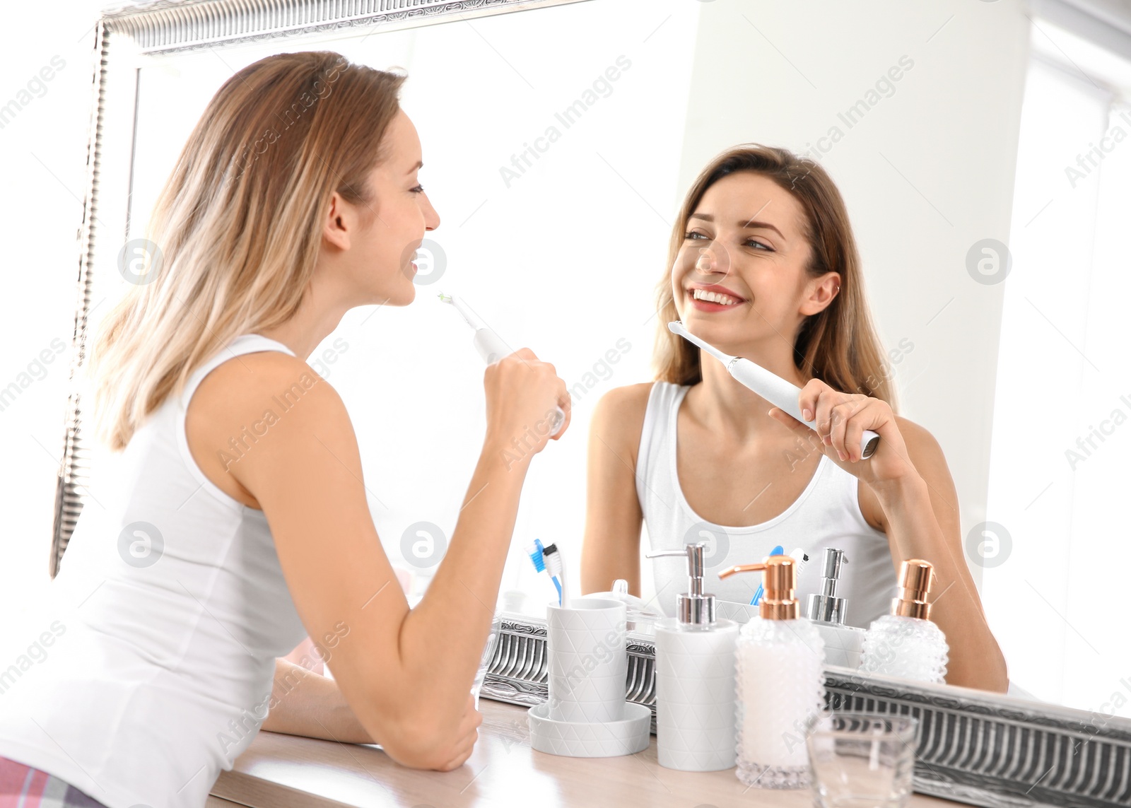 Photo of Young beautiful woman with toothbrush near mirror in bathroom. Personal hygiene