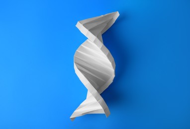 Photo of Paper model of DNA molecular chain on light blue background, top view