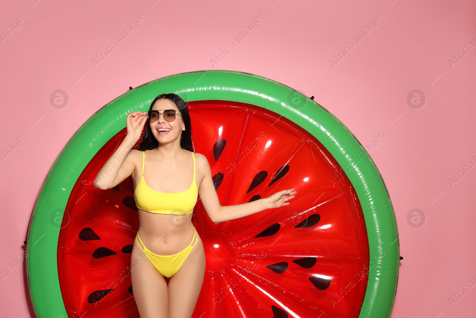 Photo of Young woman with stylish sunglasses near inflatable mattress against pink background