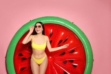 Photo of Young woman with stylish sunglasses near inflatable mattress against pink background