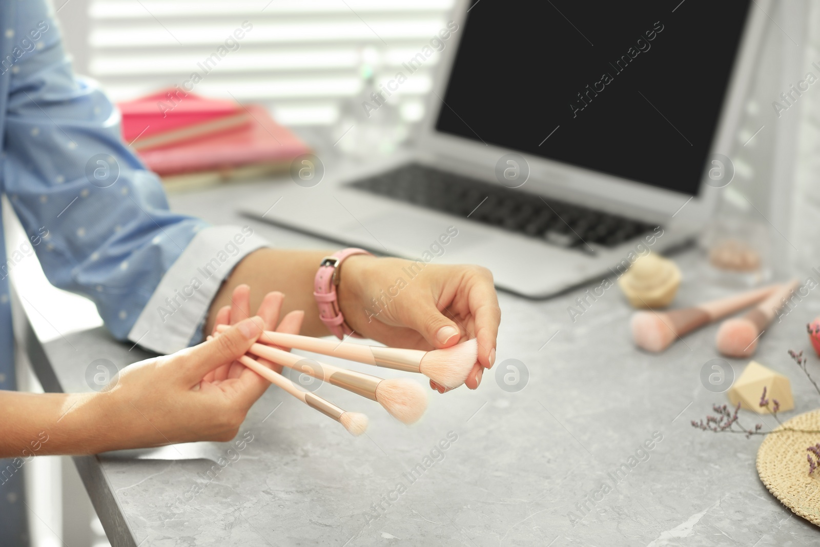 Photo of Young beauty blogger with brushes at light grey marble table, closeup