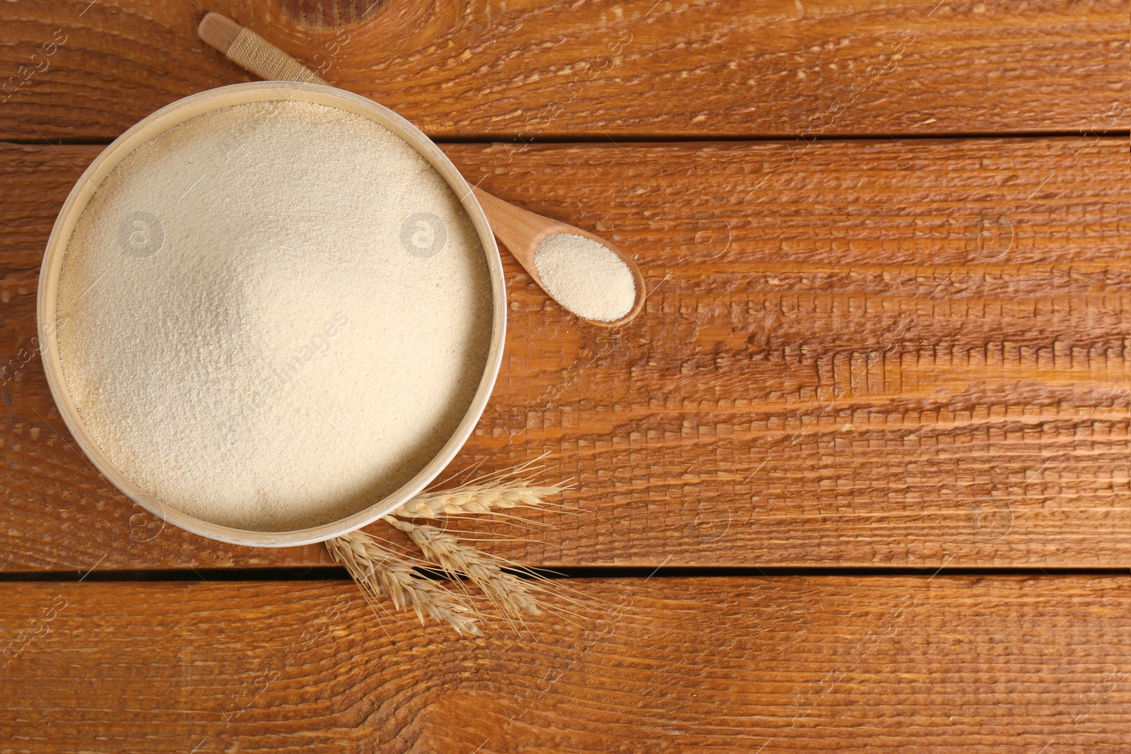 Photo of Semolina and spikelets on wooden table, flat lay. Space for text