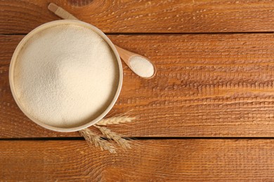 Photo of Semolina and spikelets on wooden table, flat lay. Space for text