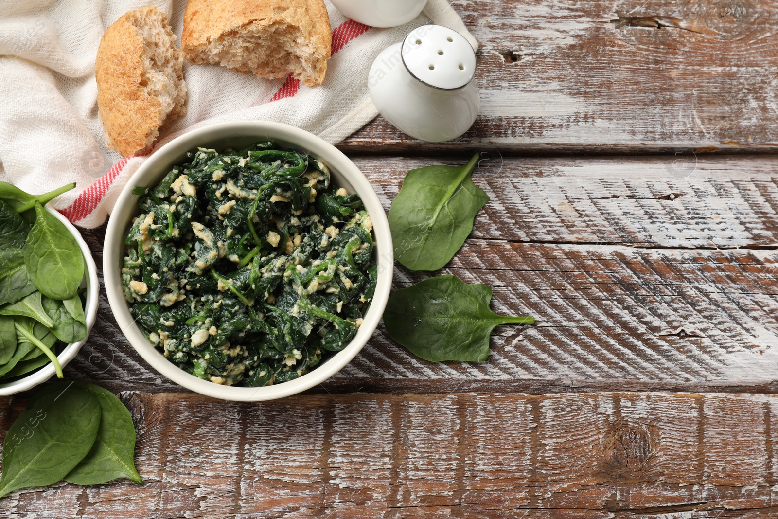 Photo of Tasty spinach dip with eggs in bowl and bread on wooden table, flat lay. Space for text