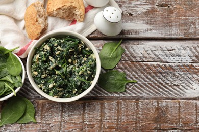 Photo of Tasty spinach dip with eggs in bowl and bread on wooden table, flat lay. Space for text