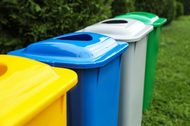 Photo of Many color recycling bins on green grass outdoors, closeup