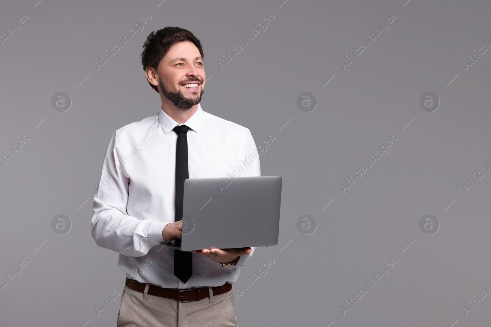 Photo of Happy man with laptop on grey background. Space for text