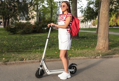 Young woman with electric kick scooter in park