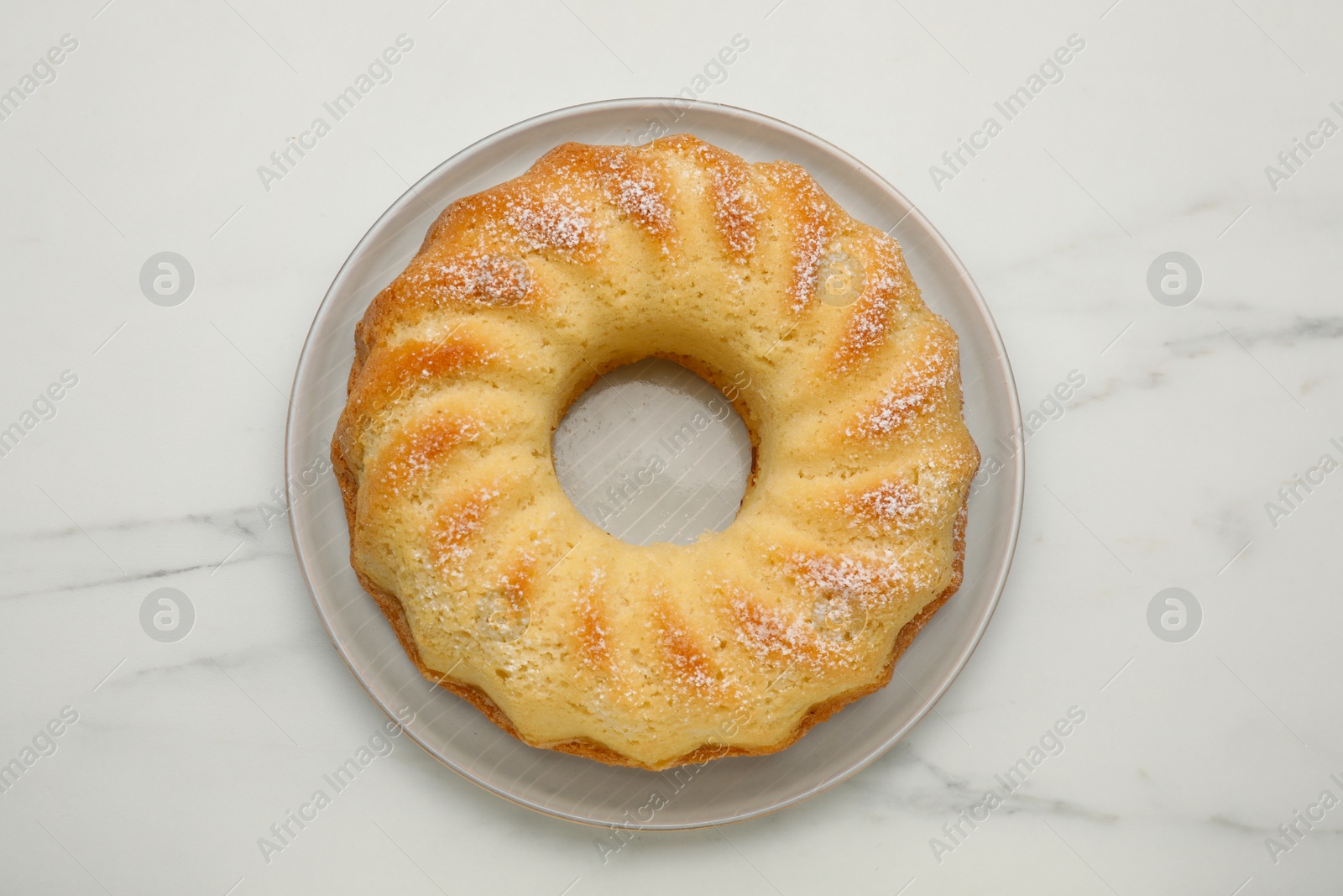 Photo of Delicious freshly baked sponge cake on white marble table, top view