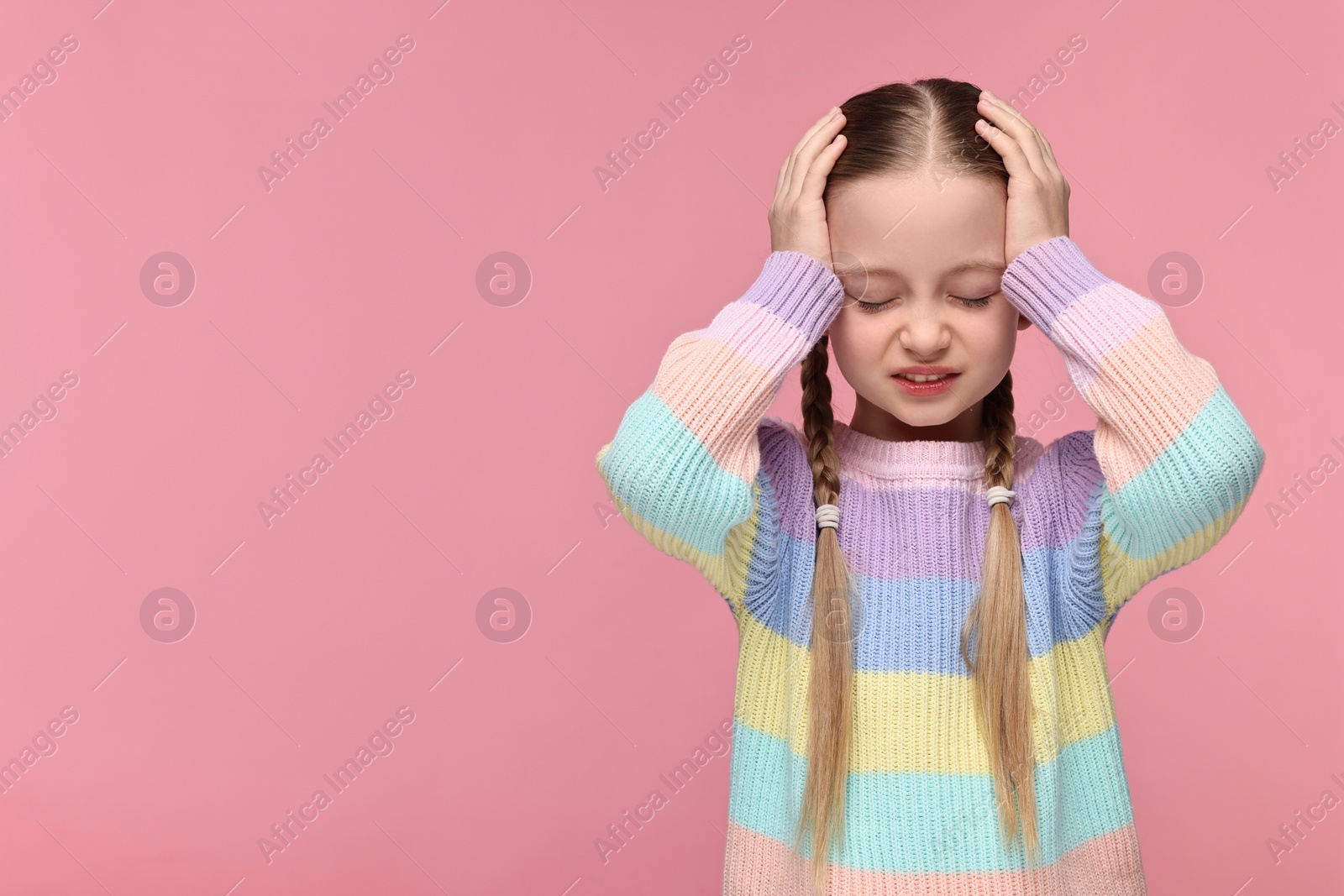 Photo of Little girl suffering from headache on pink background. Space for text