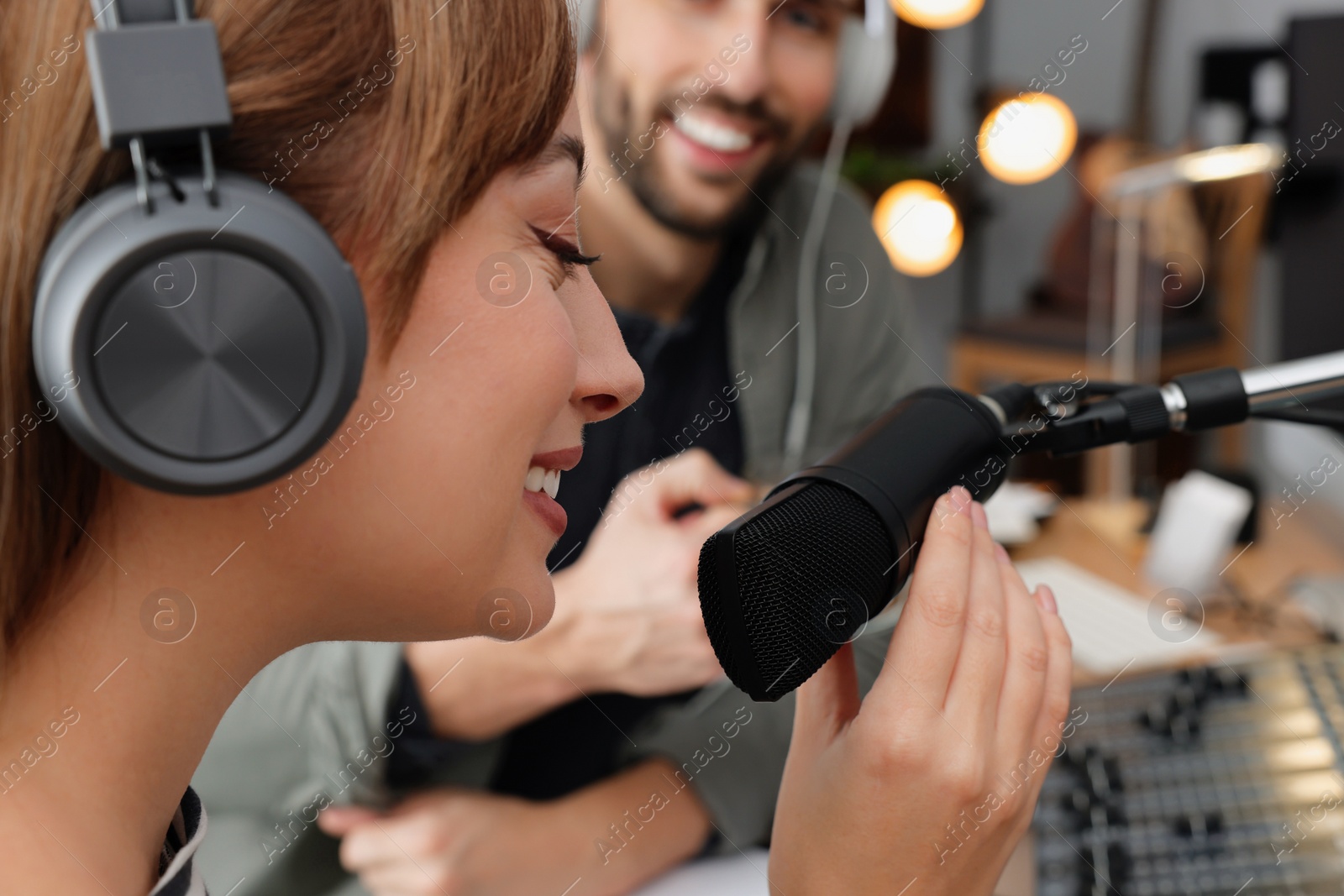 Photo of Man interviewing young woman in modern radio studio, closeup