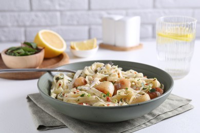 Photo of Delicious scallop pasta with spices in bowl served on white table