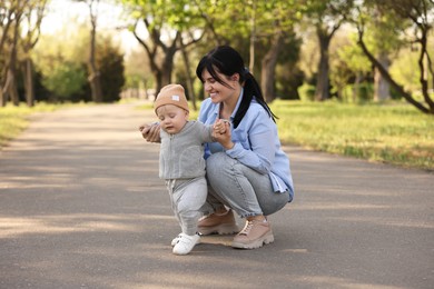 Photo of Mother supporting her baby while he learning to walk outdoors
