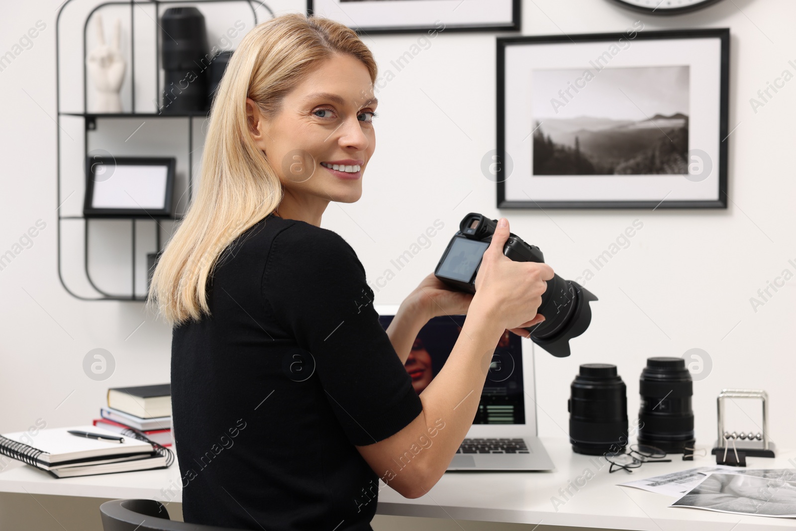 Photo of Professional photographer with digital camera at table in office