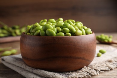 Bowl of delicious edamame beans on wooden table, closeup