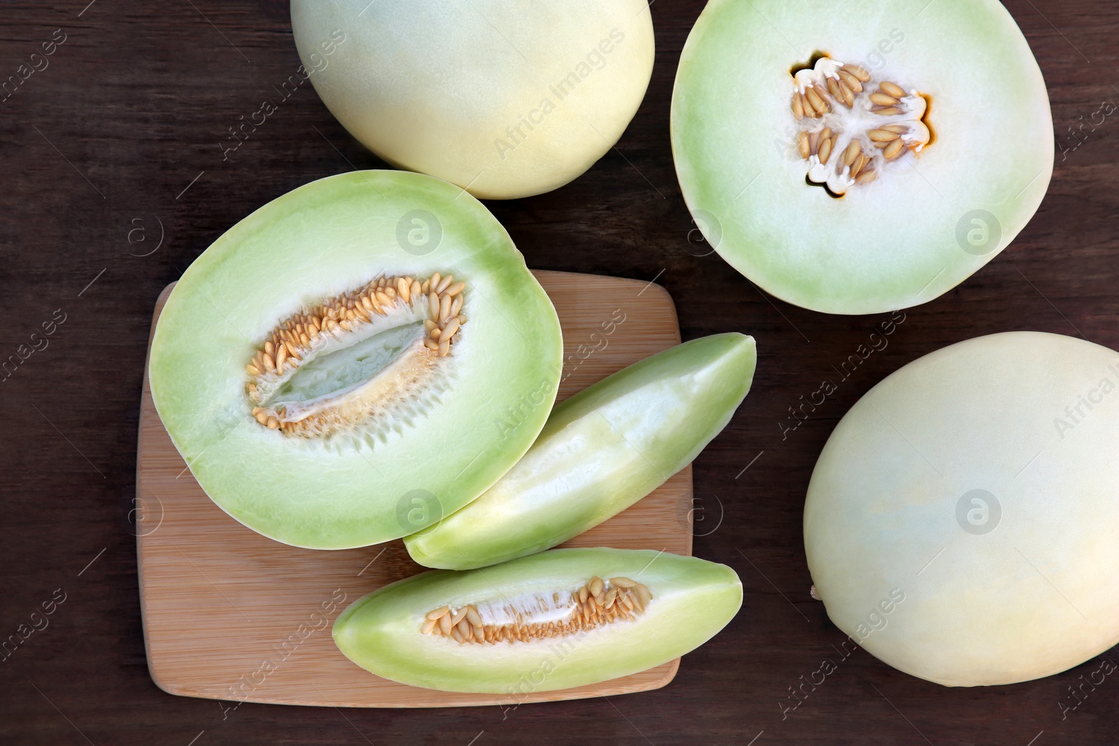 Photo of Tasty whole and cut ripe melons on wooden table, flat lay