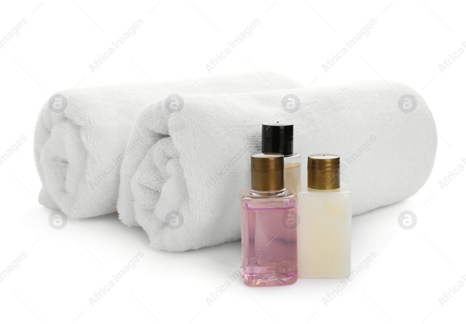 Photo of Mini bottles with cosmetic products and towels on white background. Hotel amenities