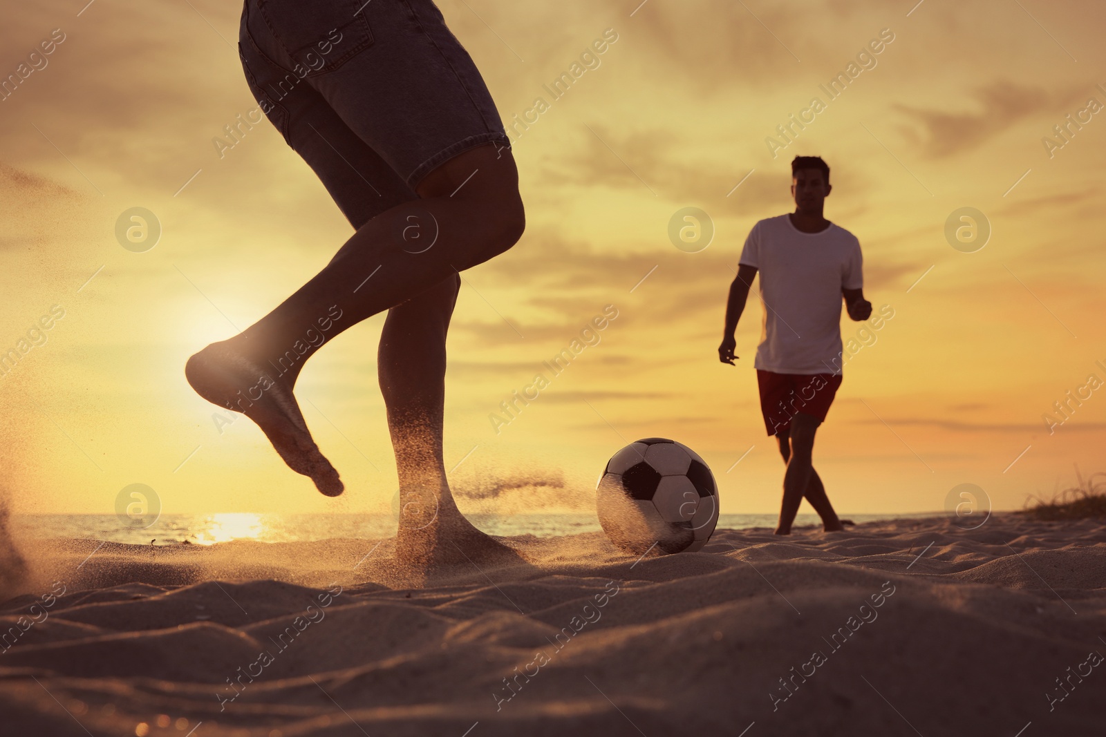 Photo of Friends playing football on beach at sunset, closeup