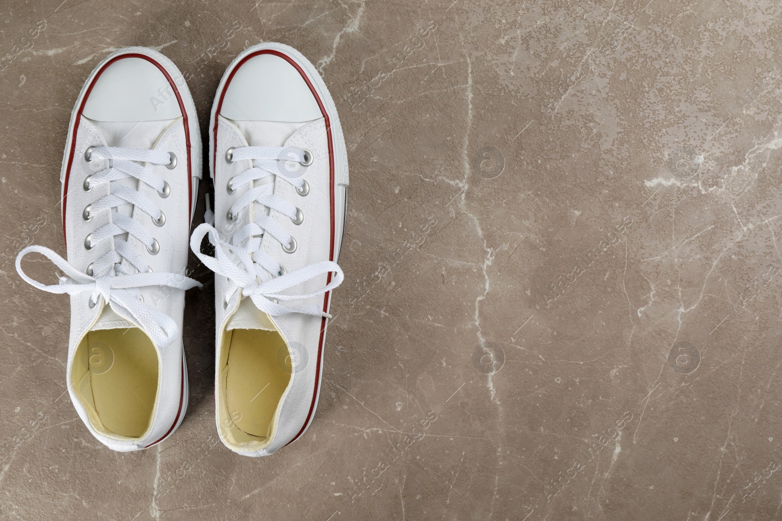 Photo of Pair of white sneakers on grey stone table, flat lay. Space for text