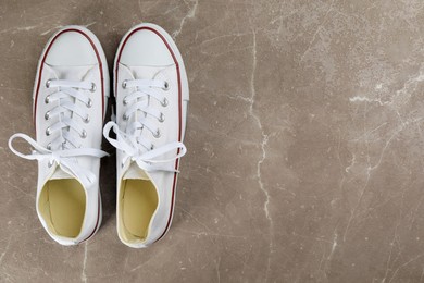 Photo of Pair of white sneakers on grey stone table, flat lay. Space for text