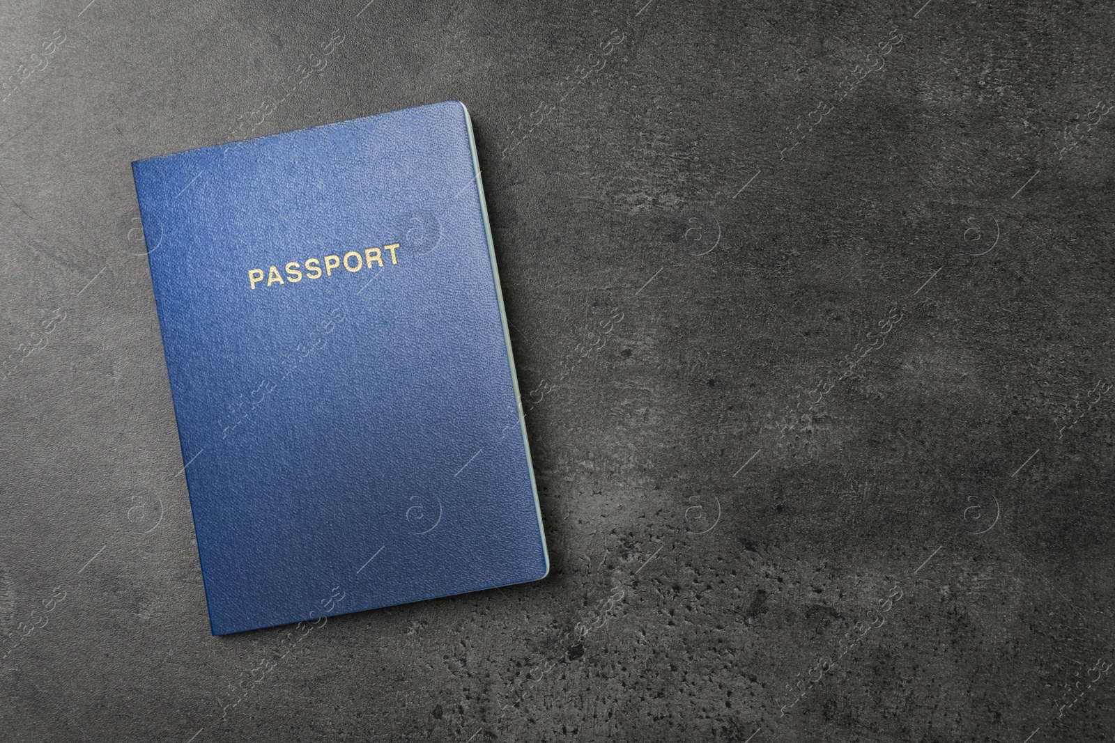 Photo of Blank blue passport on dark grey table, top view with space for text