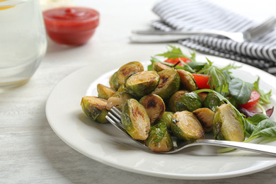 Photo of Delicious roasted brussels sprouts with different vegetables on white wooden table, closeup