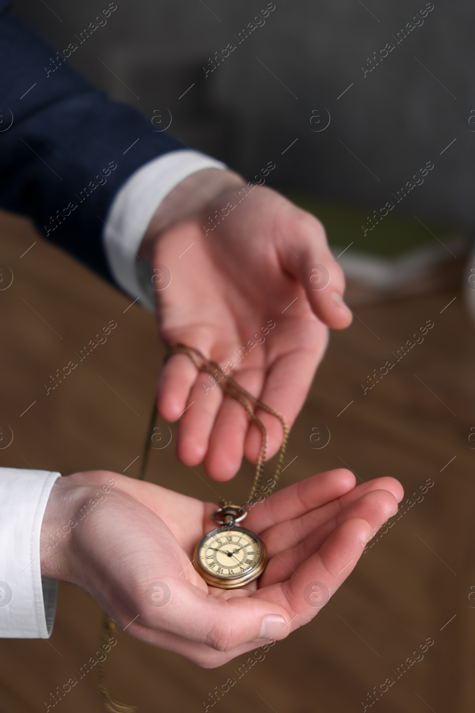 Photo of Man holding chain with elegant pocket watch on blurred background, closeup