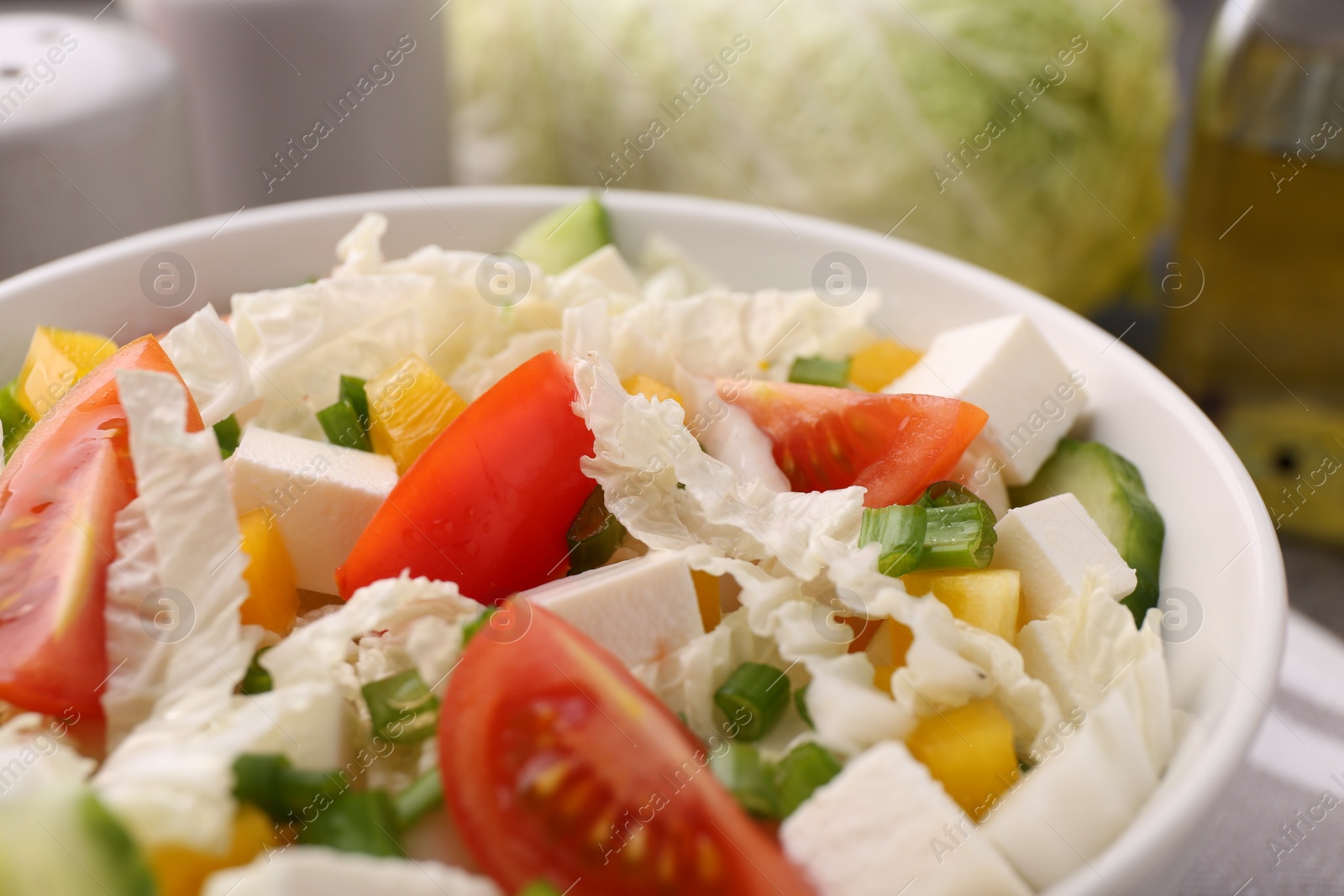 Photo of Tasty salad with Chinese cabbage, cheese, pepper, tomato and green onion on table, closeup