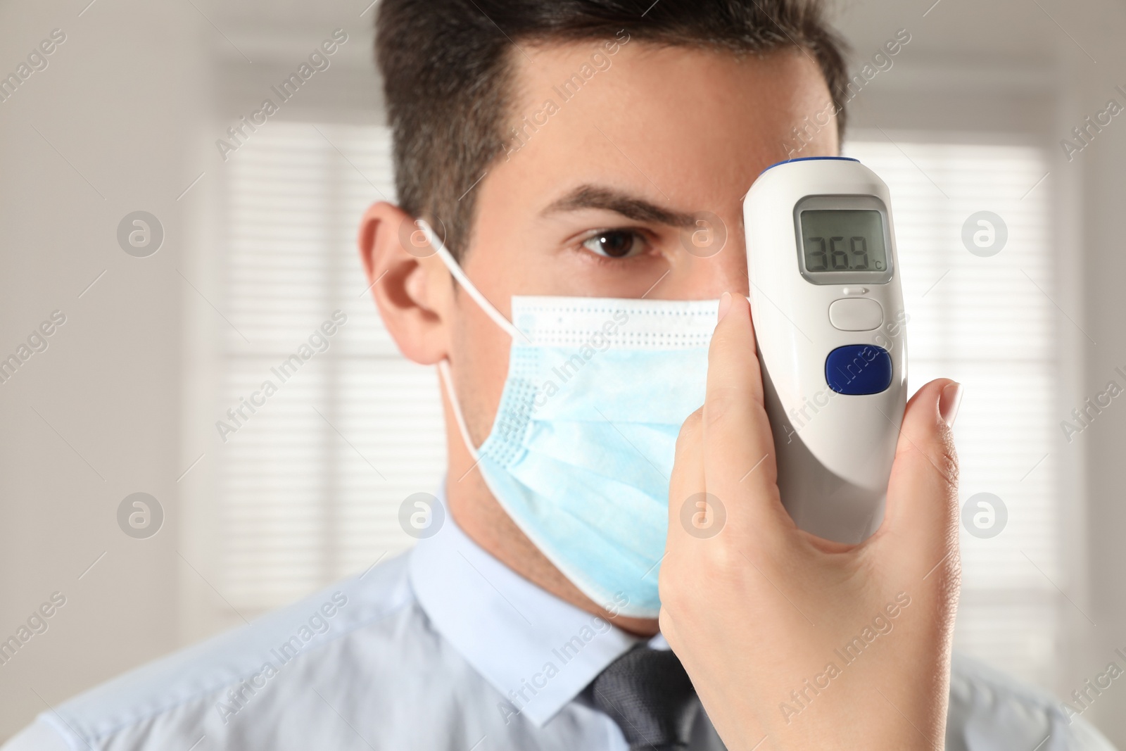 Photo of Doctor measuring man's temperature in office closeup. Prevent spreading of Covid-19