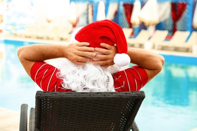 Photo of Authentic Santa Claus resting on lounge chair near pool at resort, back view