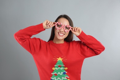 Photo of Young woman in Christmas sweater and party glasses on grey background