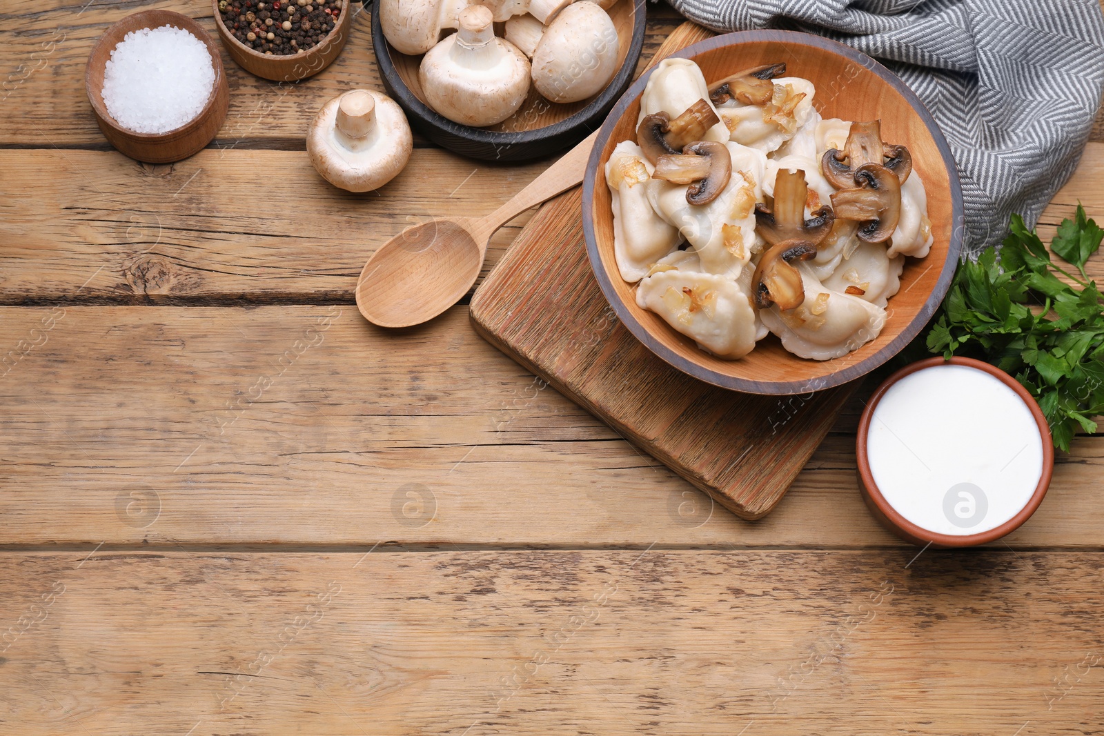 Photo of Delicious dumplings (varenyky) with potatoes, onion and mushrooms served on wooden table, flat lay. Space for text