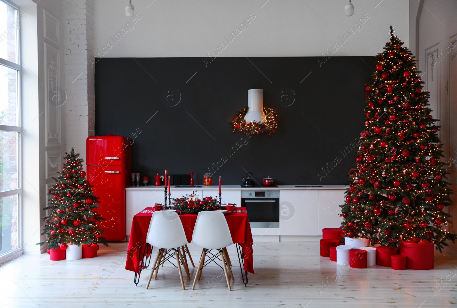 Photo of Stylish kitchen interior with festive table and decorated Christmas trees