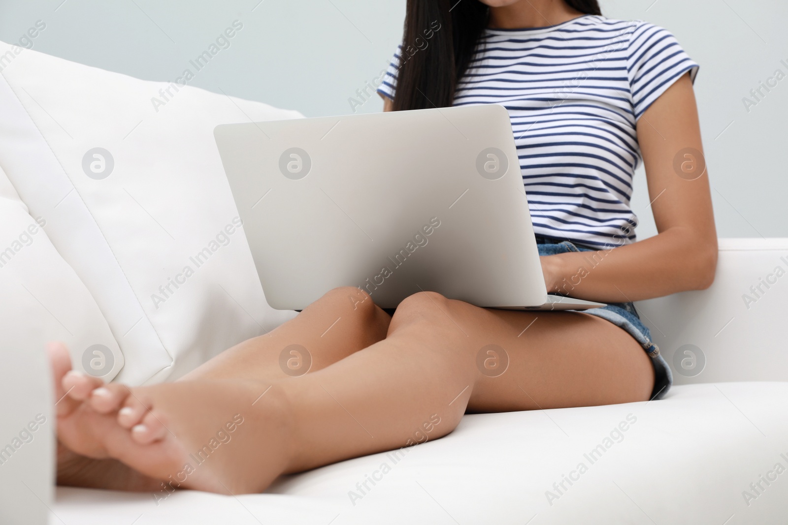 Photo of Young woman using laptop on sofa, closeup. Internet shopping