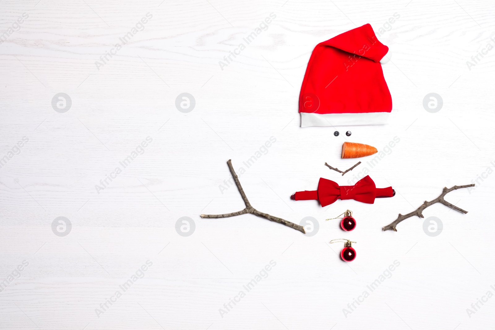 Photo of Funny snowman made with different elements on white wooden background, flat lay. Space for text