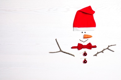 Funny snowman made with different elements on white wooden background, flat lay. Space for text