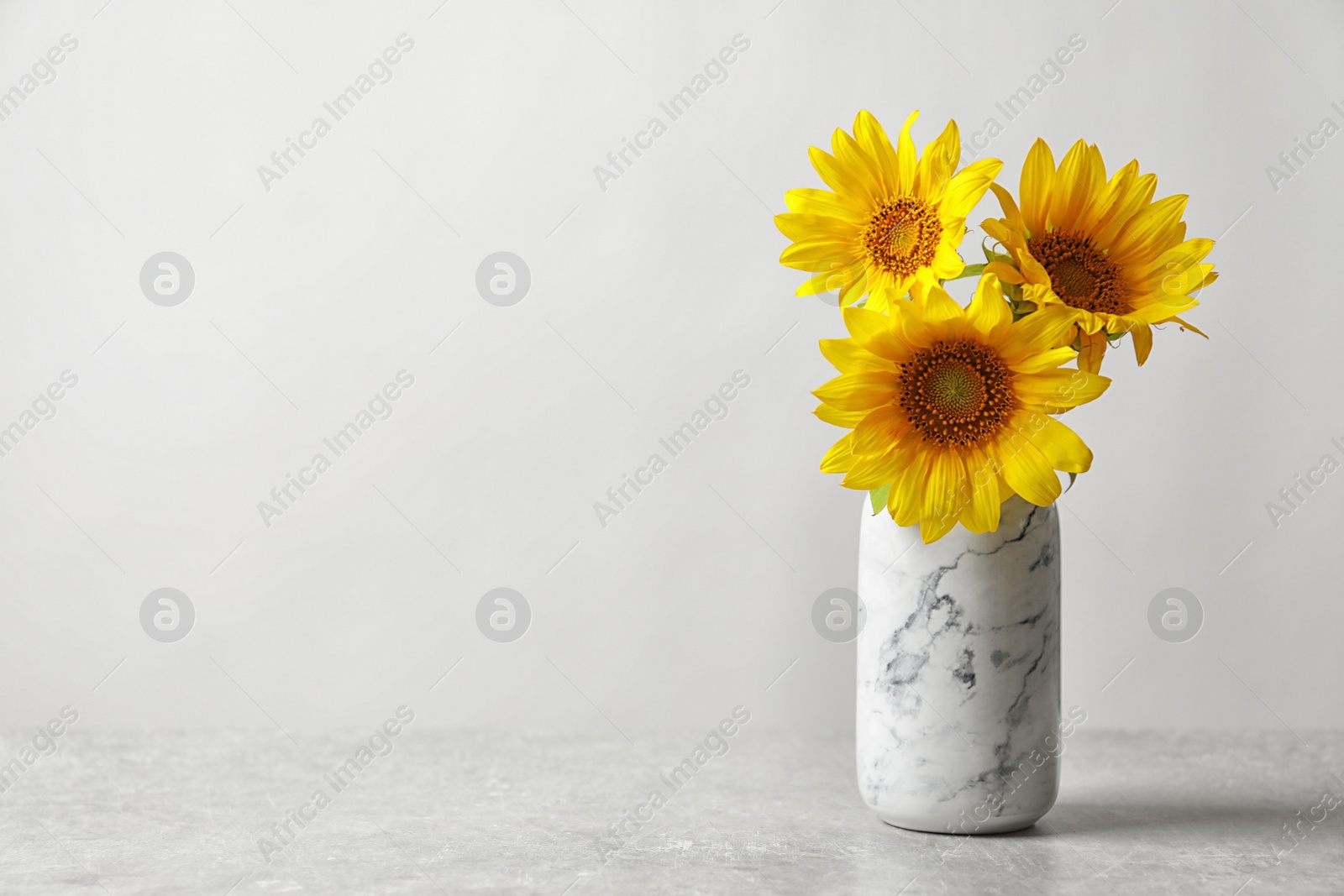 Photo of Vase with beautiful yellow sunflowers on table